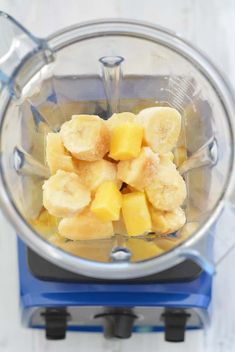 bananas and pineapple in a blender on a white table