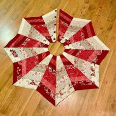 a red and white quilted umbrella sitting on top of a wooden floor