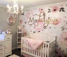 a baby's room decorated in pink and gray with flowers on the wall, crib, dressers, and bed