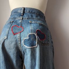 A mannequin wearing a pair of jeans with heart patches. Patch Work Denim Jeans, Heart Pocket Pants, Jean With Patches, Unique Jeans Diy, Heart Embroidered Jeans, Patchwork Baggy Jeans, Jeans Decoration Ideas, Jeans Pocket Painting, Jean Patches Ideas