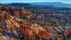 an aerial view of the hoodoos and trees in the valley below, with mountains in the distance