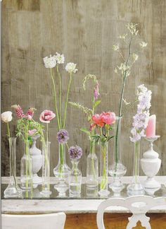 a group of vases with flowers in them on a table next to a wall