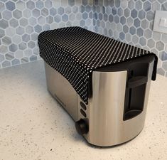 a silver toaster sitting on top of a counter next to a tile backsplash