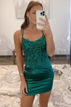 a woman taking a selfie wearing a green dress and holding a cell phone in her hand