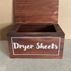 a wooden box with the words dryer sheets written in white ink on it sitting on a table