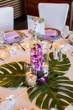 the table is set with purple flowers and place cards for guests to sit down at