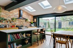 an open kitchen and dining area with brick walls, wooden flooring and skylights