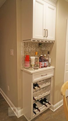 a wine rack in the corner of a kitchen with white cabinets and countertop space