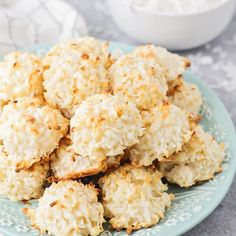 a blue plate topped with coconut cookies next to a bowl of cottage cheese in the background