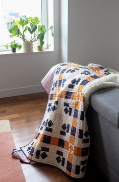 a couch with a blanket sitting on top of it next to a potted plant