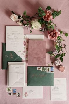 the wedding stationery is laid out with flowers and greenery