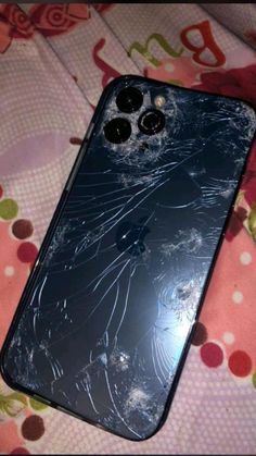 an iphone that has been smashed and is laying on a bed with the screen cracked off