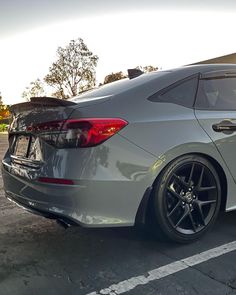 the rear end of a silver car parked in a parking lot