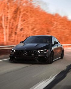 the mercedes amg cla is driving on a road with trees in the background