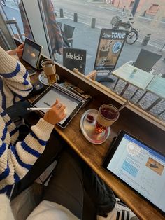 a person sitting at a table with a tablet and a drink in front of them