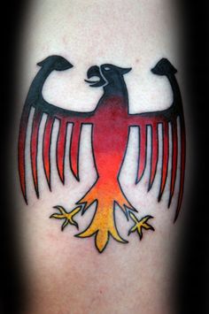 an eagle tattoo on the back of a woman's thigh, with red and yellow colors