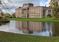 a large building sitting on top of a lush green field next to a body of water