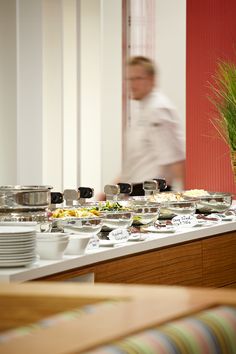 a chef is in the background preparing food on a buffet table with plates and bowls