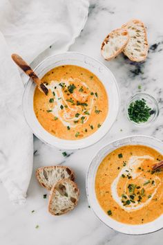 two bowls of soup on a marble table with bread and parsley in the background