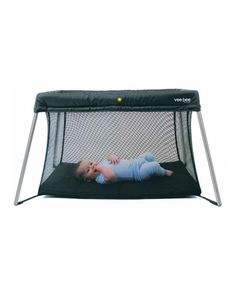 a baby laying on top of a black mat in front of a white wall with a net