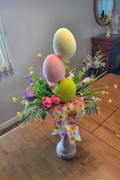 a vase filled with flowers and balls on top of a table