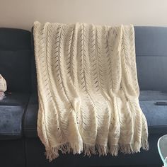 a white knitted blanket sitting on top of a couch next to a blue chair