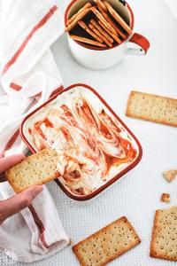 a person dipping crackers into a bowl of dip