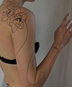 a woman with a flower tattoo on her back and arm, holding something in her hand