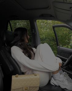 a woman sitting in the driver's seat of a car with her handbag