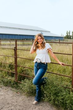 a woman leaning against a fence posing for a photo