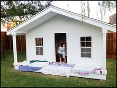 a man standing in the doorway of a small white house that is being constructed into a bed