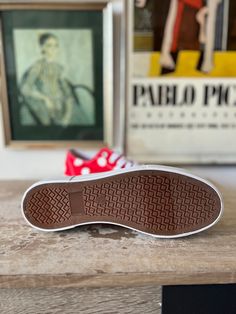 a pair of shoes sitting on top of a wooden table next to a framed painting