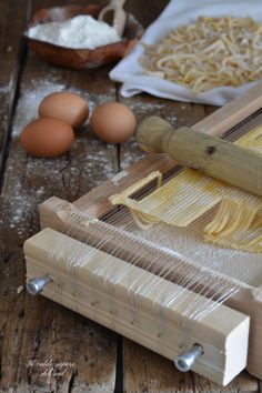 an image of pasta being made on a wooden table with eggs and other ingredients around it