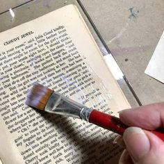 a person holding a brush over an open book