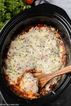 a slow cooker filled with lasagna sauce and topped with parmesan cheese