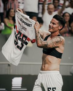 a shirtless man holding up a jersey in front of a large group of people