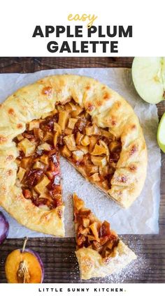 an apple pie with one slice cut out and some apples around it on a wooden table