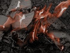 an open book sitting on top of a pile of dirt next to fire and rocks