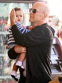 an older man holding a small child in front of a vending machine