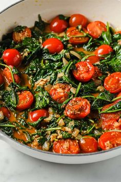 a pan filled with spinach and tomatoes