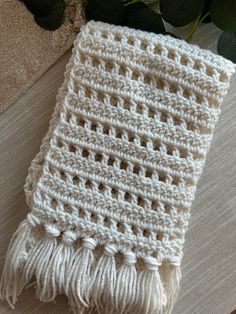 a white crocheted blanket sitting on top of a table next to a plant