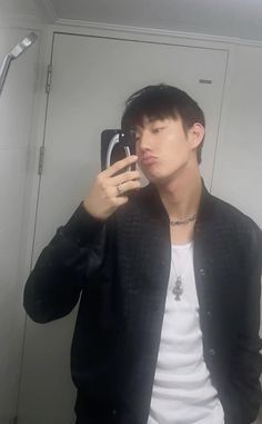 a young man taking a selfie in the mirror with his cell phone up to his ear