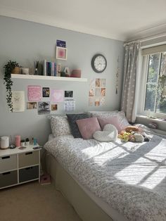 a bed sitting in a bedroom next to a window with lots of pictures on the wall