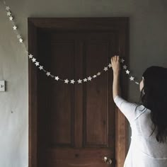 a woman is hanging garlands on the door to hang them in front of her