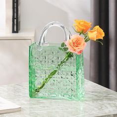 a green bag with flowers in it sitting on a table