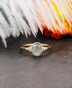 a close up of a ring on a table with feathers and flowers in the background