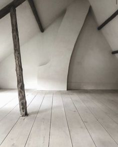 an empty room with wooden floors and exposed beams on the ceiling is seen in this image