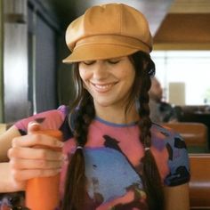 a woman wearing a hat is looking at her cell phone while sitting in a restaurant