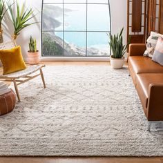 a living room filled with furniture and a large window overlooking the ocean on a sunny day