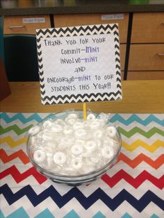 a bowl filled with lots of white donuts sitting on top of a colorful table cloth